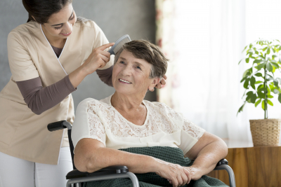 caregiver combing the hair of senior woman in wheel chair