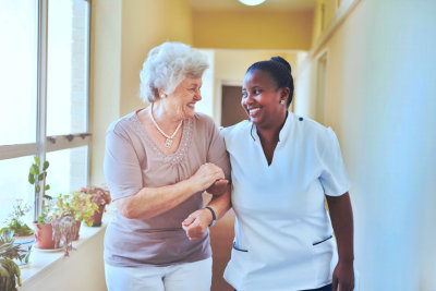 caregiver and elderly woman walking down the hallway